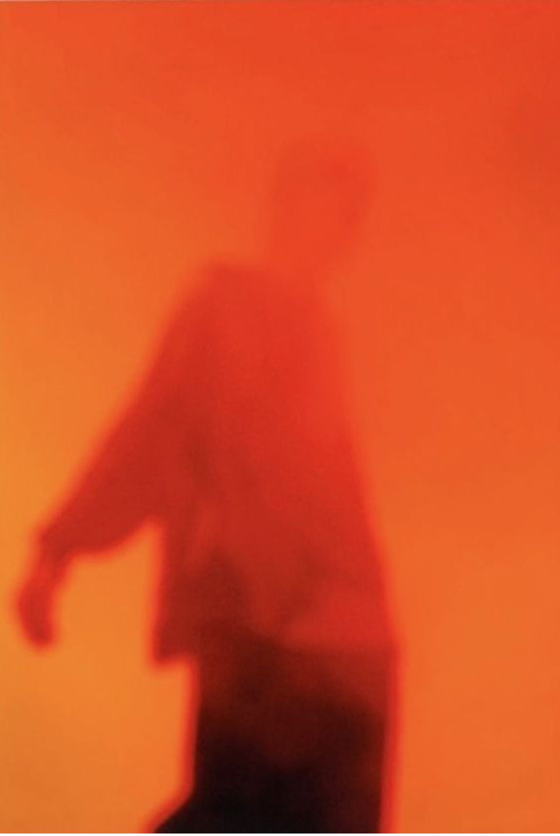 Blurred figure walking, silhouetted against a vivid orange-red ground