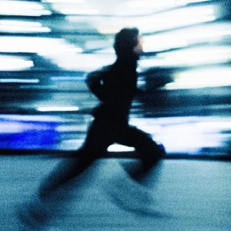 Blurred photograph of a person sprinting, the background smeared with motion