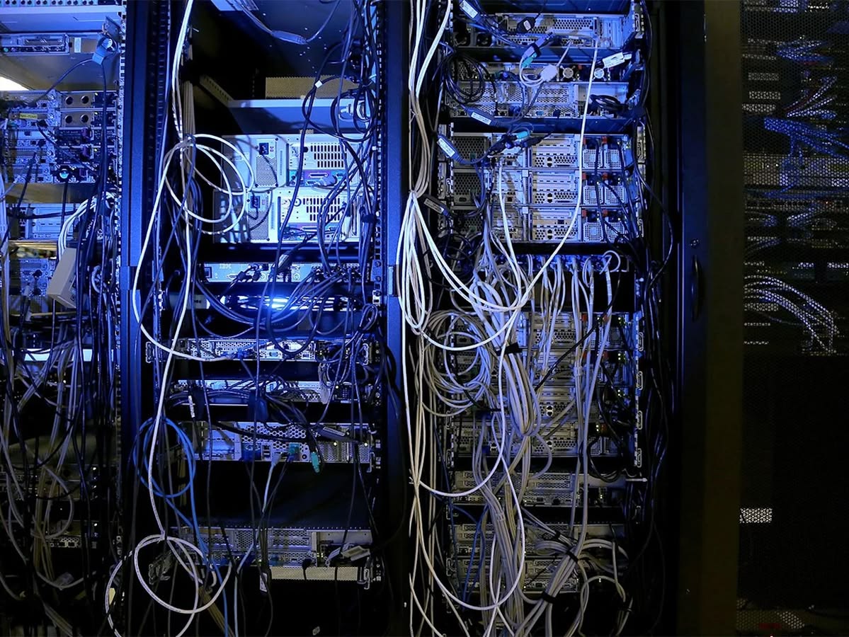 Server racks glowing blue, white cables cascading in darkness