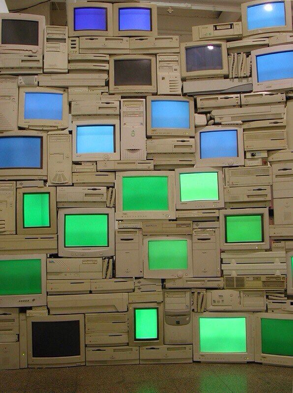 Wall of stacked beige CRT monitors glowing green and blue